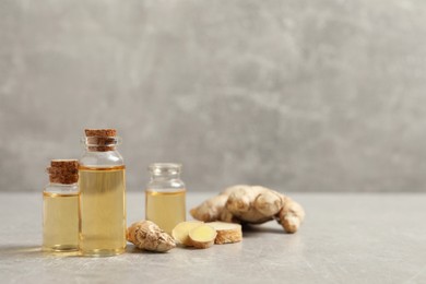 Photo of Ginger essential oil in bottles on light grey marble table. Space for text