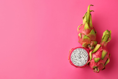 Photo of Delicious cut and whole dragon fruits (pitahaya) on pink background, flat lay. Space for text