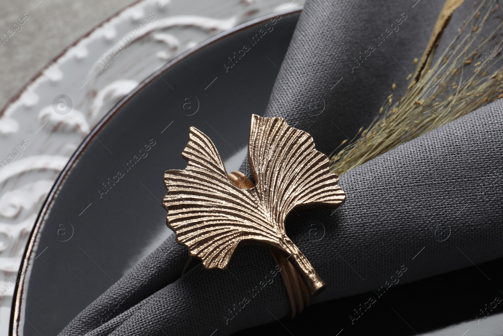 Photo of Fabric napkin and decorative ring for table setting on gray plate, closeup