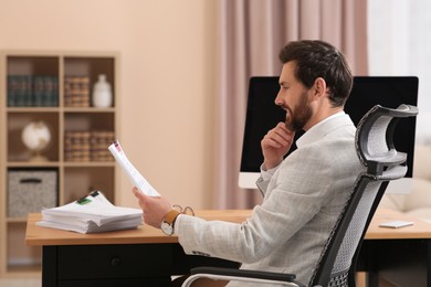 Happy businessman working with documents at wooden table in office