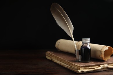 Photo of Feather pen, bottle of ink, old book and parchment scroll on wooden table. Space for text