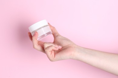 Photo of Woman holding jar of cream on pink background, closeup