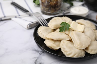 Delicious dumplings (varenyky) with tasty filling, butter and parsley served on white marble table, closeup. Space for text