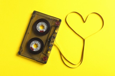 Photo of Music cassette and heart made with tape on yellow background, top view. Listening love song