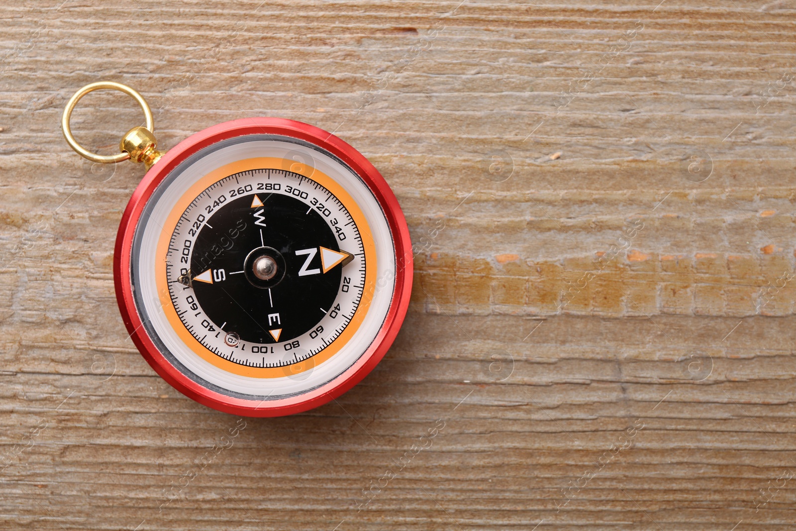 Photo of One compass on wooden table, top view. Space for text