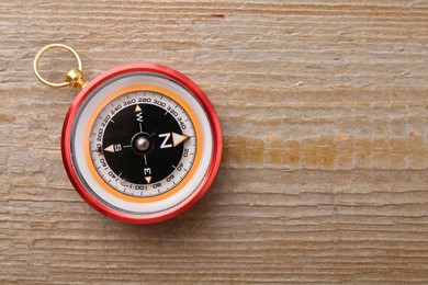 One compass on wooden table, top view. Space for text