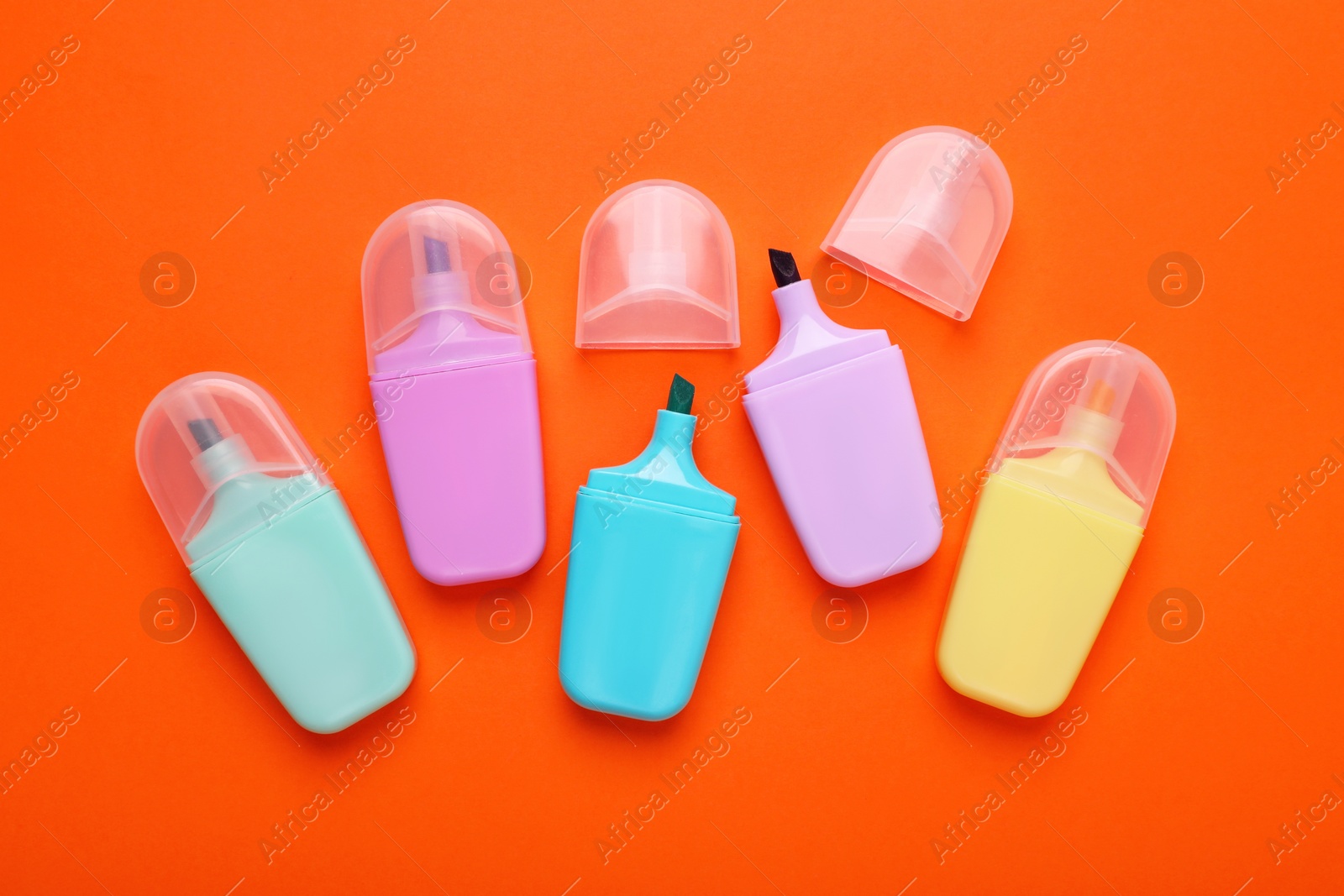 Photo of Many colorful markers on orange background, flat lay