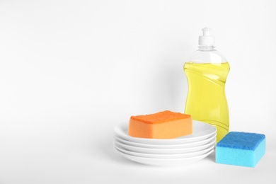 Detergent, plates and sponges on white background. Clean dishes