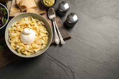 Photo of Delicious pasta with burrata cheese served on black table, flat lay. Space for text