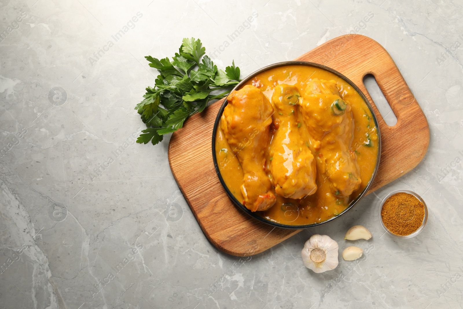 Photo of Tasty chicken curry and ingredients on grey textured table, flat lay. Space for text