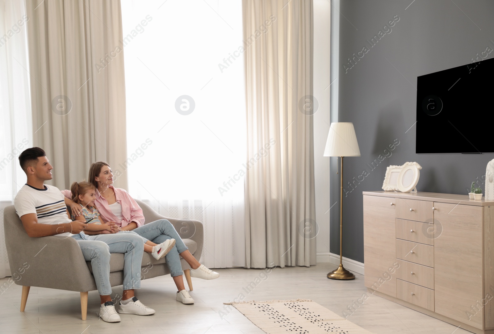 Photo of Happy family watching TV on sofa at home