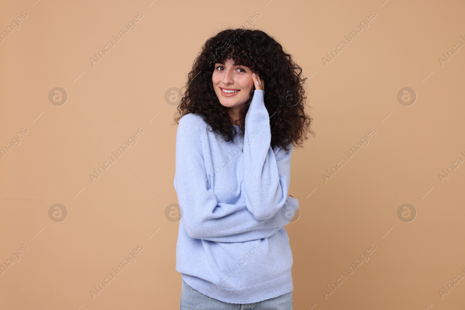 Photo of Happy young woman in stylish light blue sweater on beige background