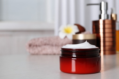 Photo of Jar of body care product on table against blurred background. Space for text