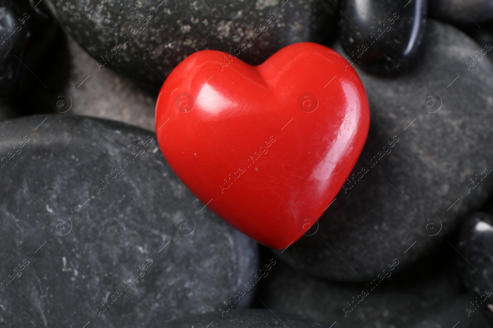 Photo of Red decorative heart on pebble stones, closeup