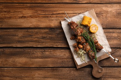 Photo of Metal skewers with delicious meat and vegetables served on wooden table, top view. Space for text