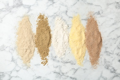 Stripes of different flour types on marble background, top view