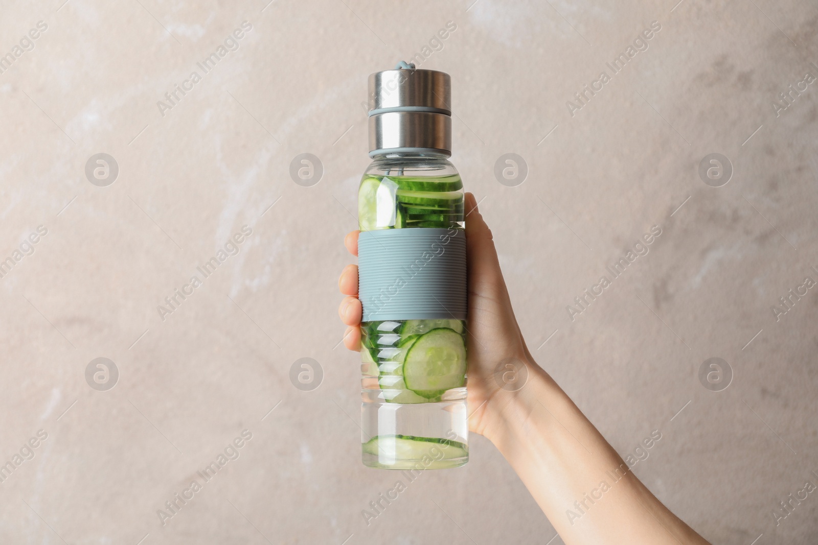 Photo of Young woman holding bottle with fresh cucumber water on color background