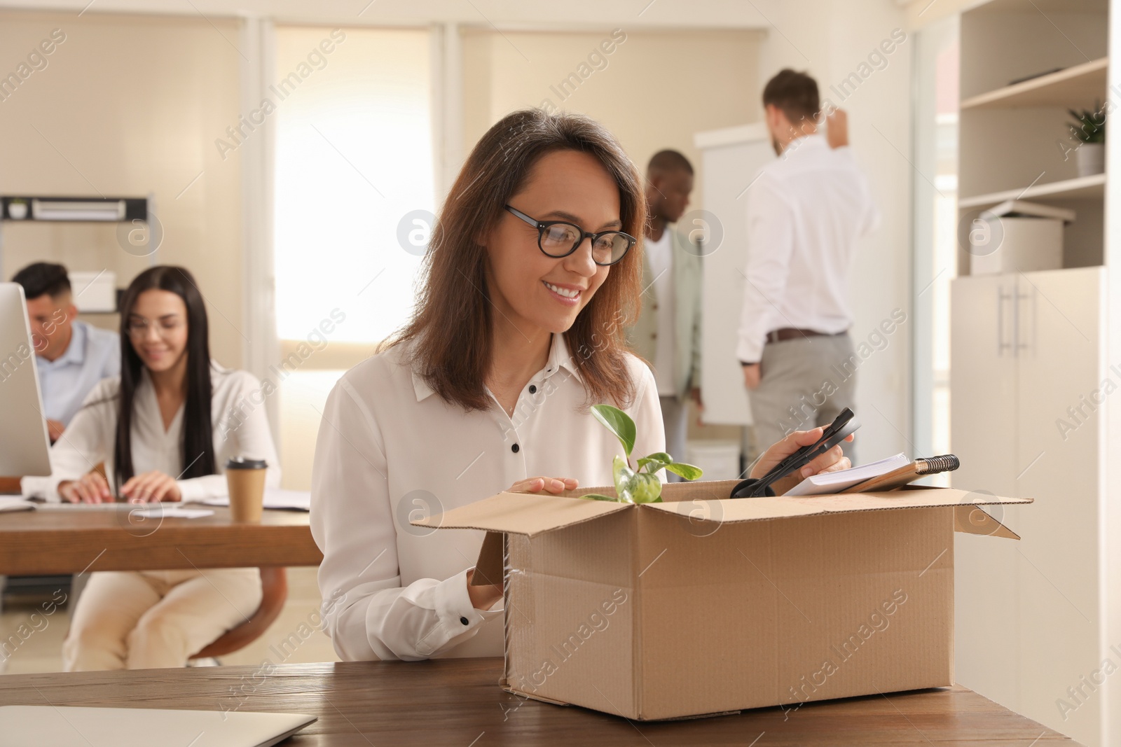 Photo of New coworker unpacking box with personal items at workplace in office