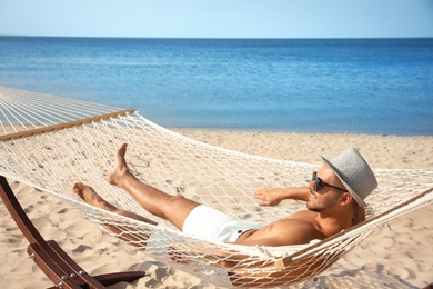 Photo of Young man relaxing in hammock on beach