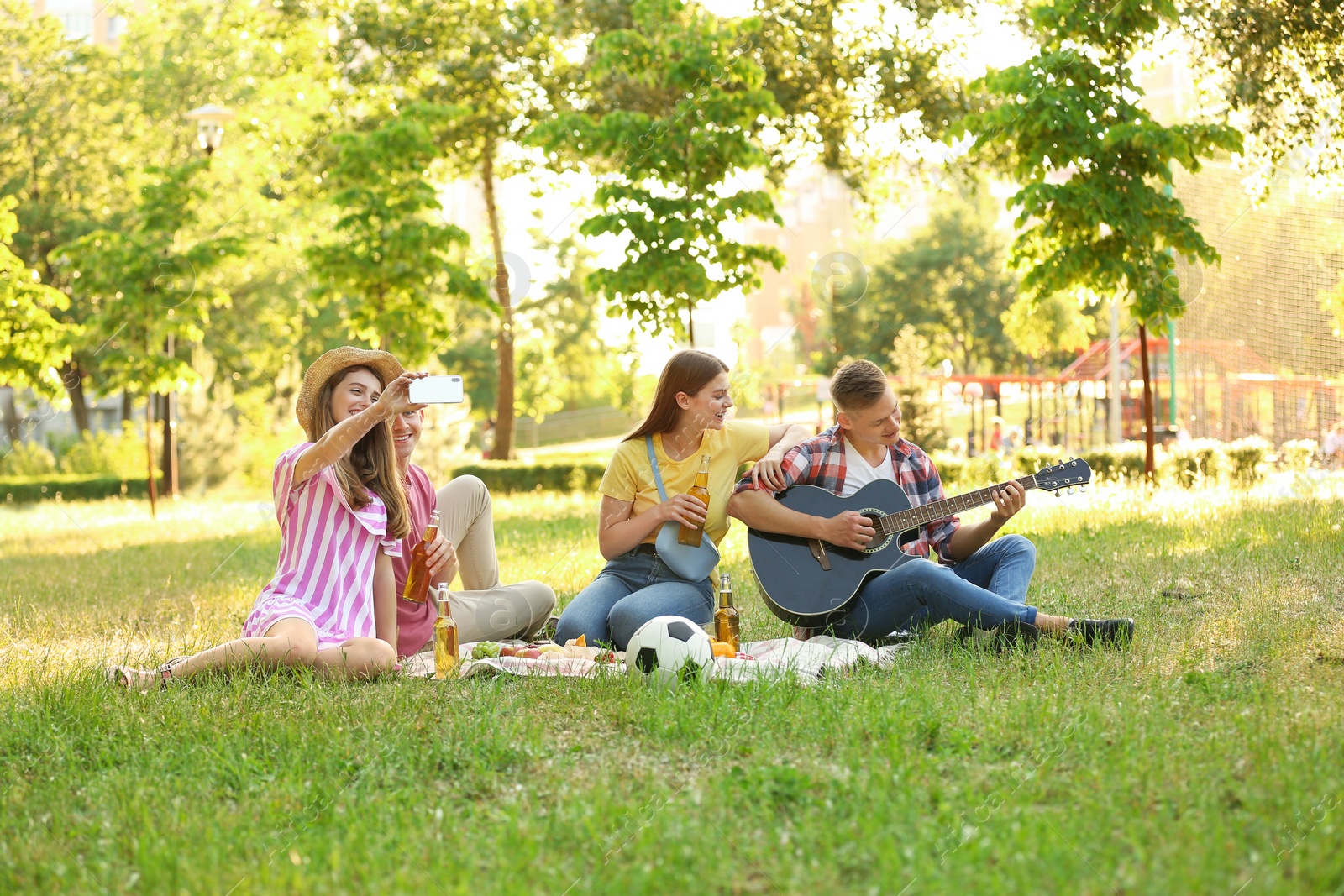 Photo of Young people enjoying picnic in park on summer day