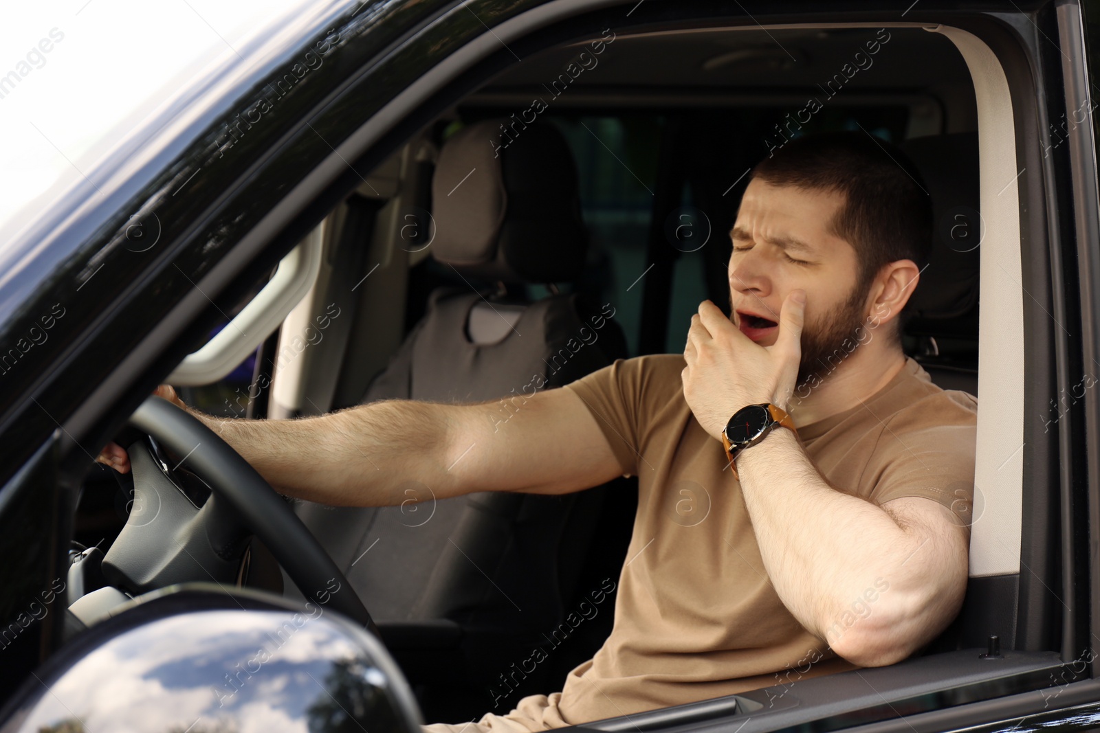 Photo of Tired man yawning while driving his modern car