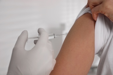 Doctor vaccinating woman against Covid-19 in clinic, closeup