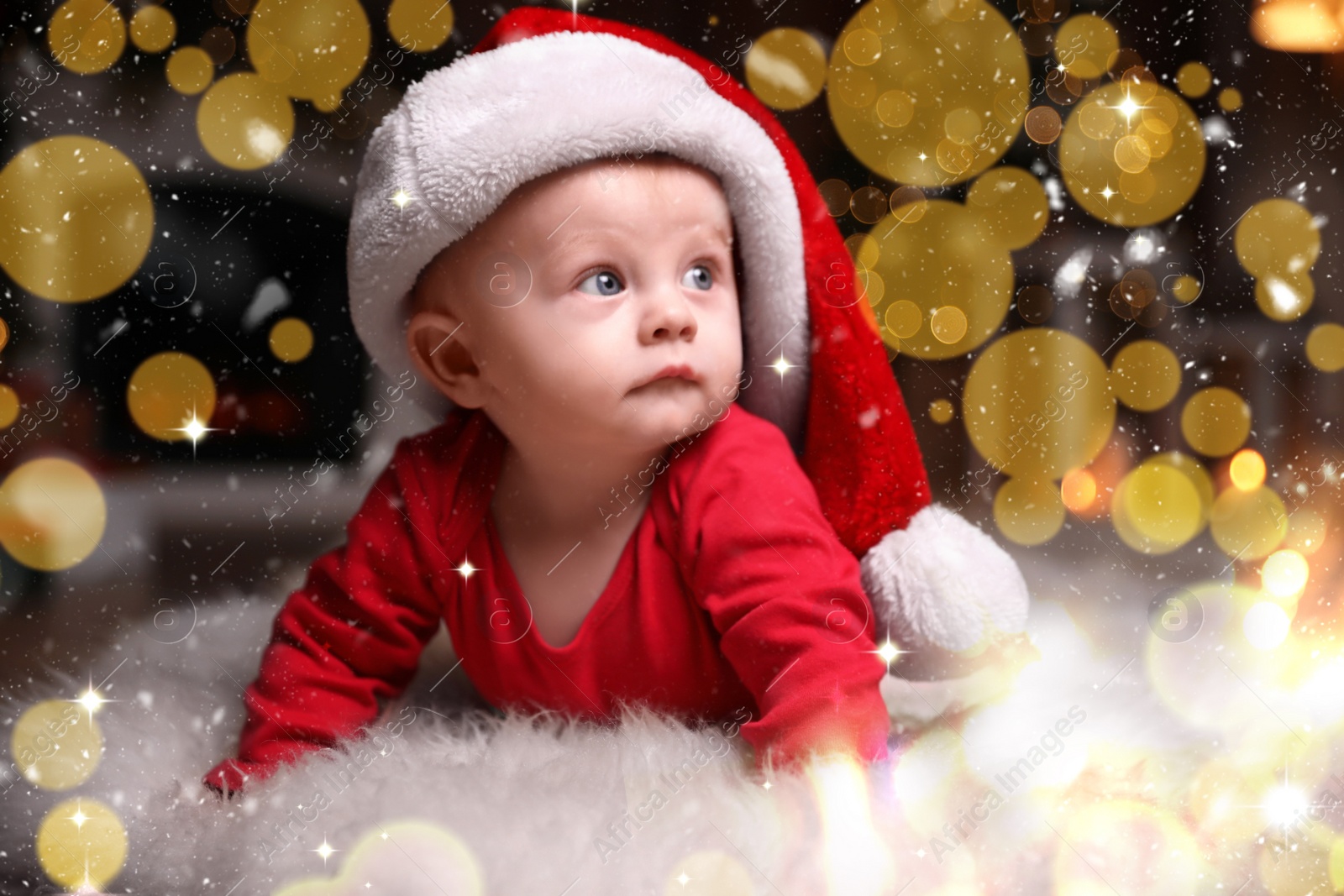 Image of Cute little baby in red pajamas and Santa hat on floor against blurred festive lights. Christmas suit