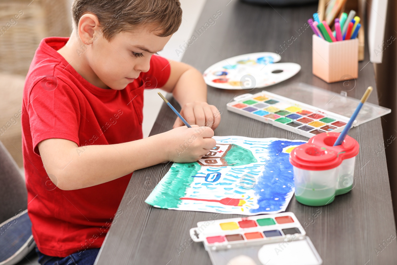 Photo of Little child painting at table in room