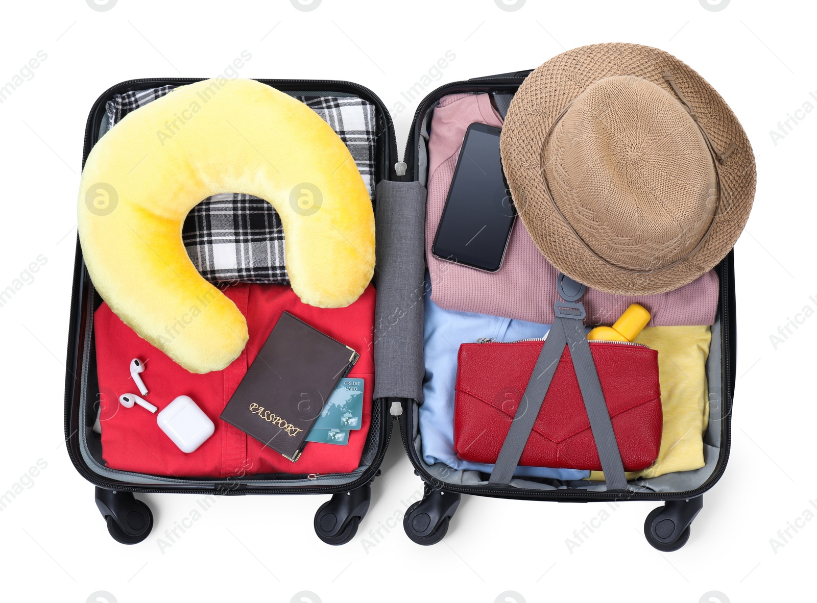 Photo of Soft travel pillow, hat, passports and other items in open suitcase isolated on white, top view