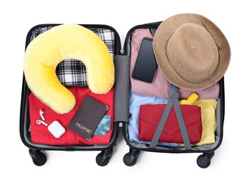 Soft travel pillow, hat, passports and other items in open suitcase isolated on white, top view