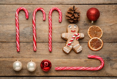 Flat lay composition with tasty candy canes and Christmas decor on wooden table