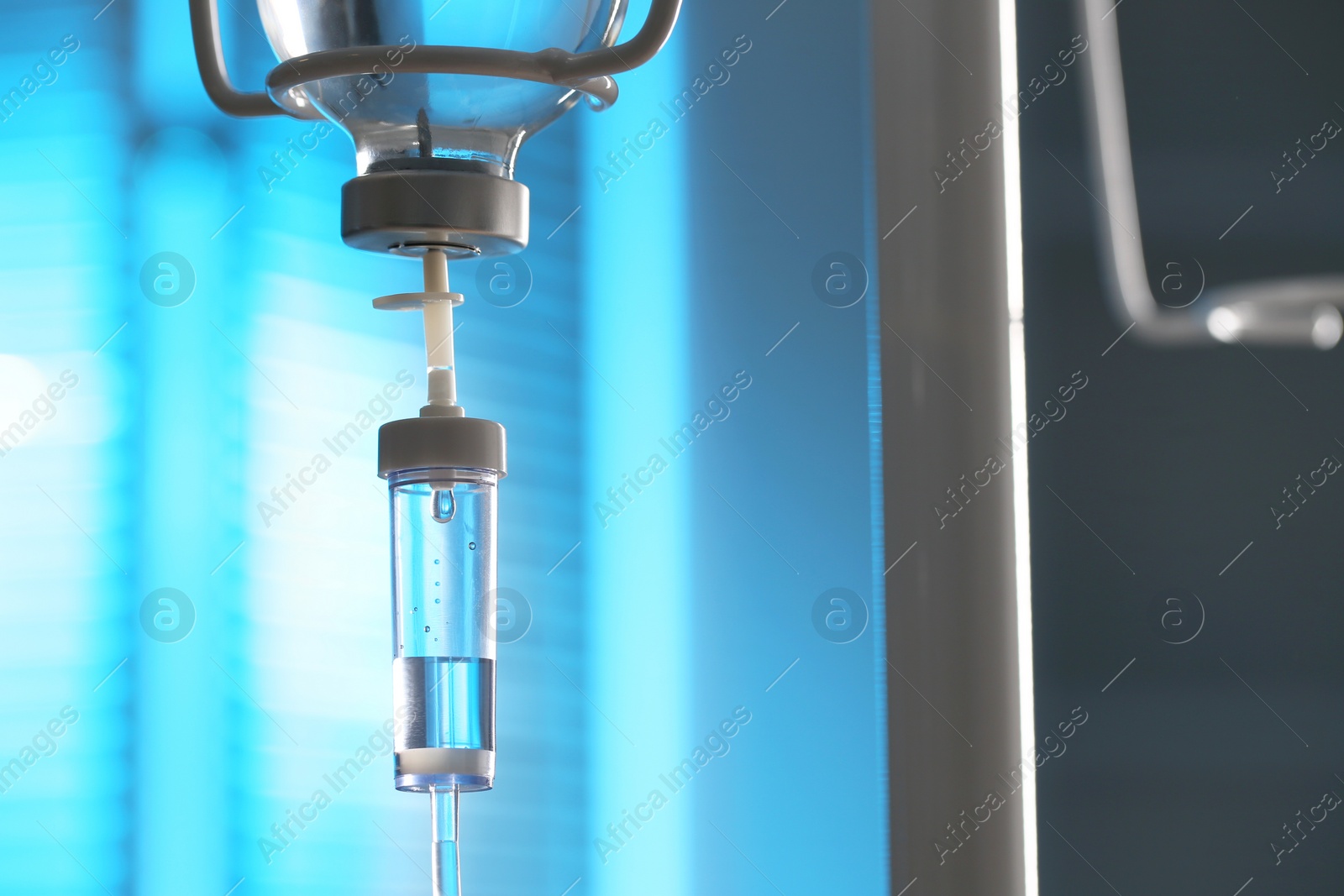 Photo of IV drip against blurred light blue background, space for text