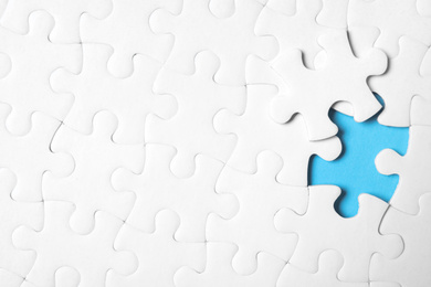 Photo of Blank white puzzle with separated piece on light blue background, top view. Space for text
