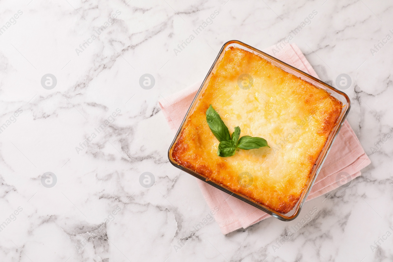 Photo of Tasty cooked lasagna in baking dish on white marble table, top view. Space for text