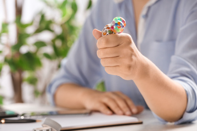 Photo of Woman squeezing colorful slime in office, closeup. Antistress toy