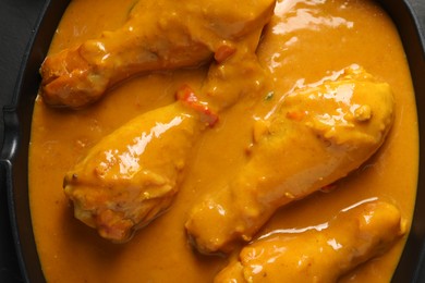 Photo of Tasty chicken curry in black frying pan, top view