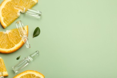 Photo of Skincare ampoules with vitamin C, slices of orange and leaves on light green background, flat lay. Space for text