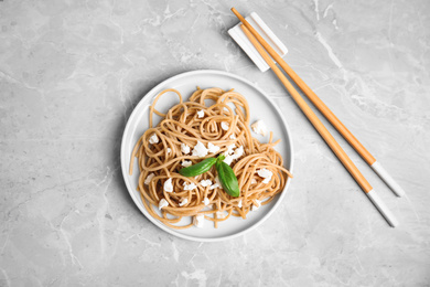 Tasty buckwheat noodles with chopsticks on light grey table, flat lay