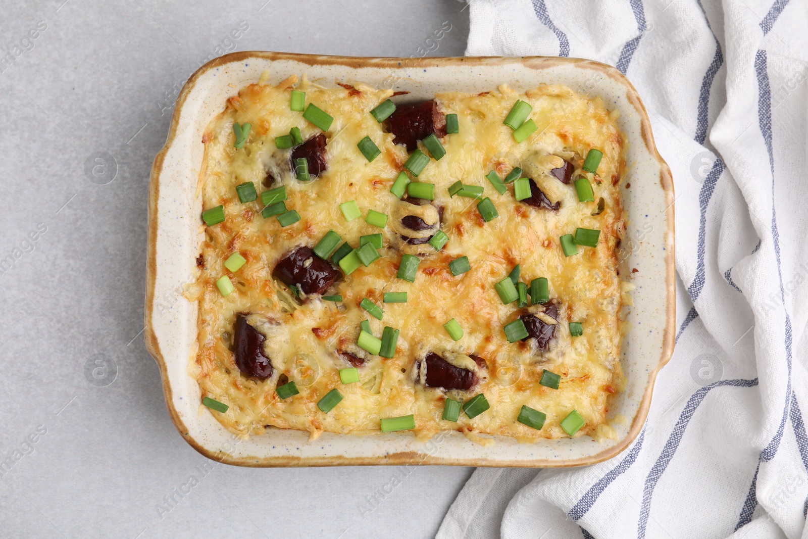 Photo of Tasty sausage casserole with green onions in baking dish on white table, top view