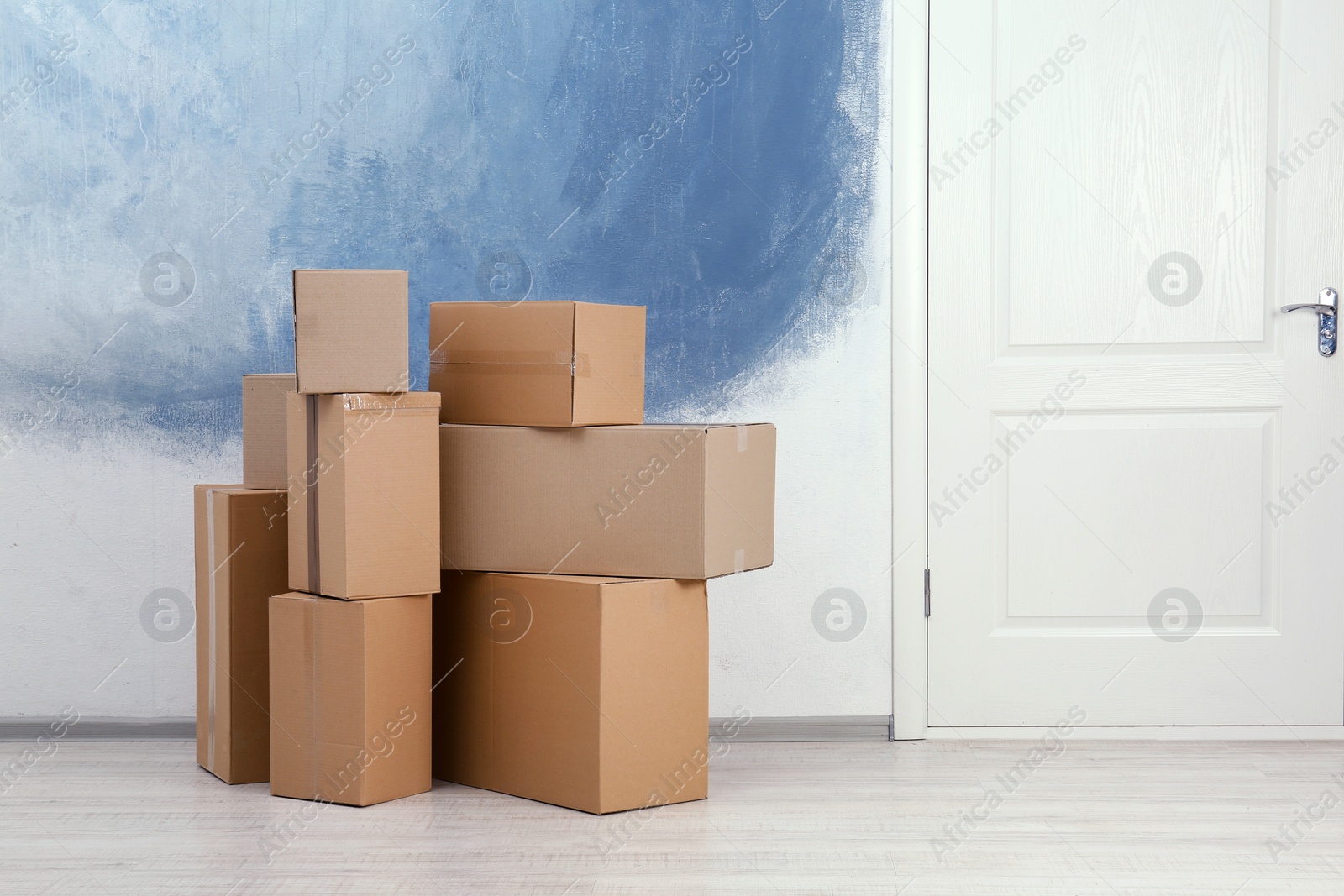 Photo of Cardboard boxes on floor near apartment entrance. Mockup for design