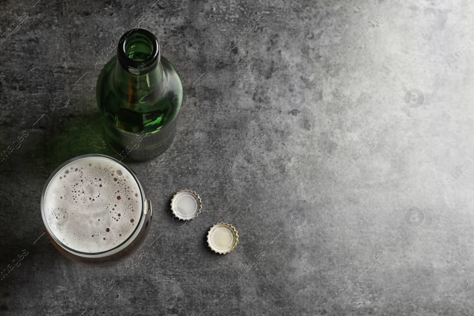 Photo of Bottle and glass with tasty cold beer on grunge background, top view