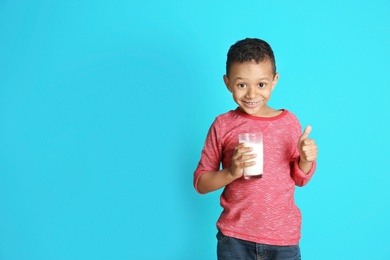 Photo of Adorable African-American boy with glass of milk on color background