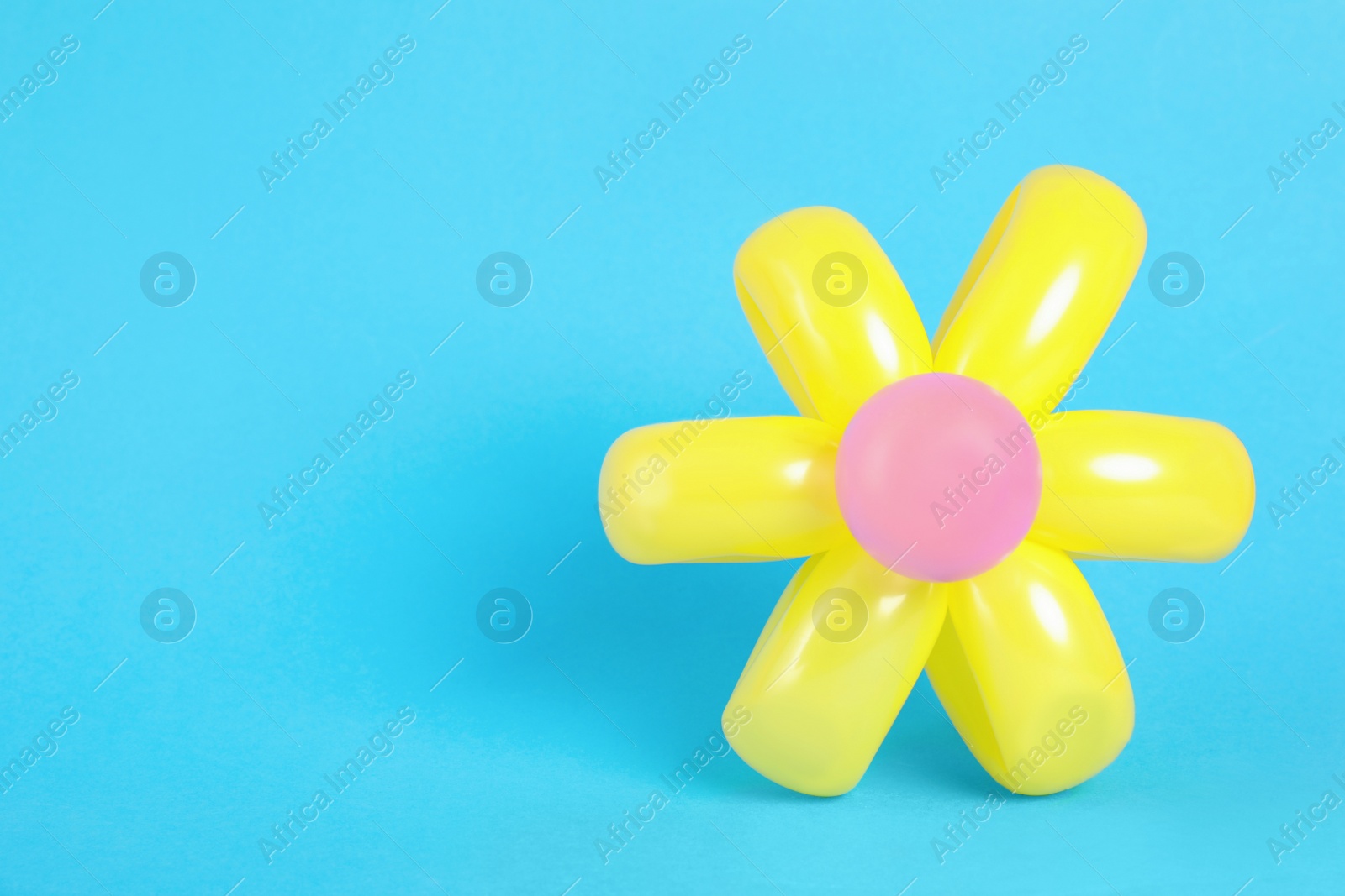 Photo of Flower figure made of modelling balloon on color background. Space for text