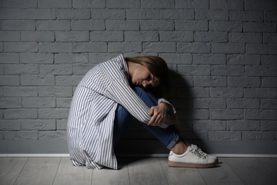 Photo of Lonely woman suffering from depression near brick wall