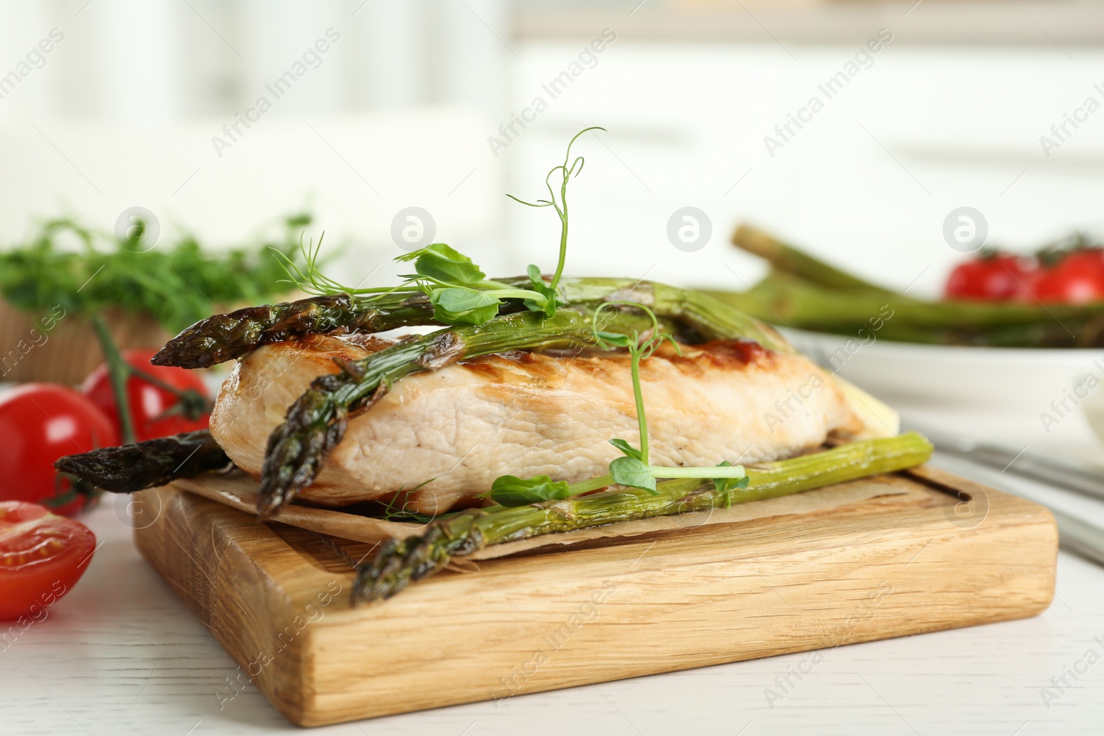 Photo of Tasty grilled chicken fillet served with asparagus and sprouts on white wooden table