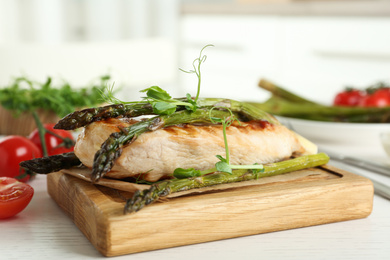 Tasty grilled chicken fillet served with asparagus and sprouts on white wooden table