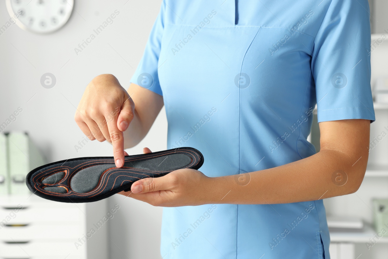 Photo of Female orthopedist showing insole in hospital, closeup