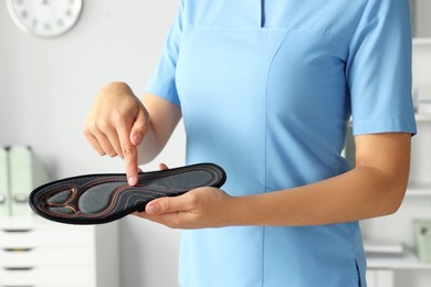 Female orthopedist showing insole in hospital, closeup