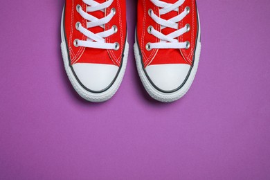 Photo of Pair of new stylish red sneakers on purple background, flat lay. Space for text