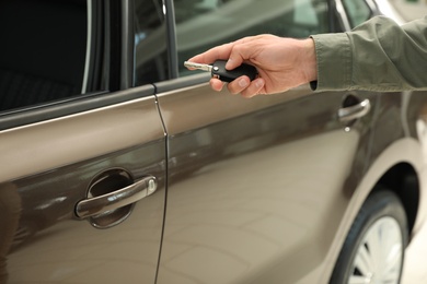 Young man checking alarm system with car key indoors, closeup